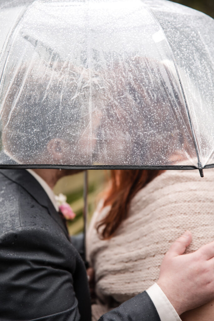 couple kisses under rain covered umbrella during elopement in Alaska